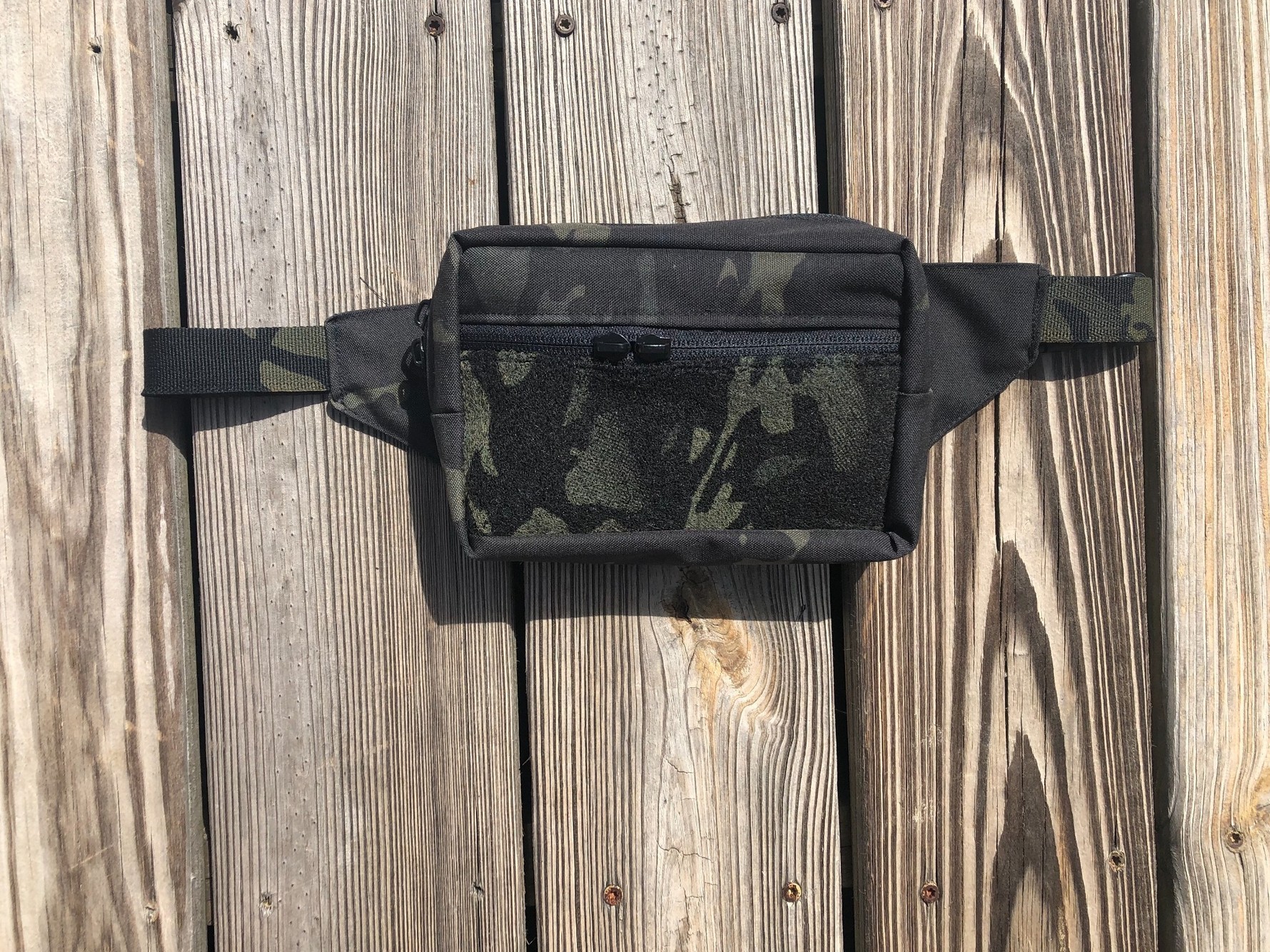 Finished camouflage utility waist pack with zippered compartment and front hook-and-loop field